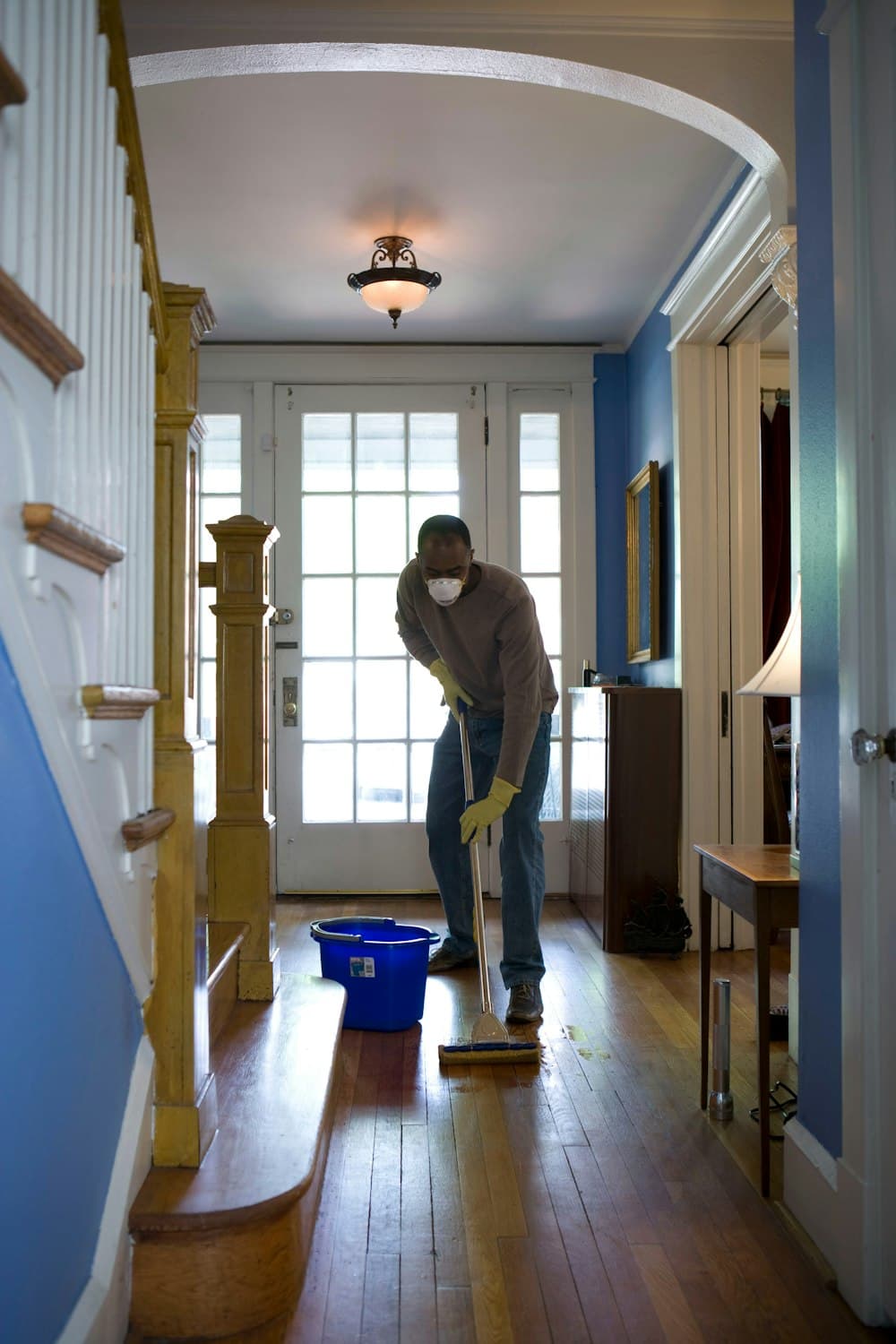 A professional cleaner mopping the hallway of a family home