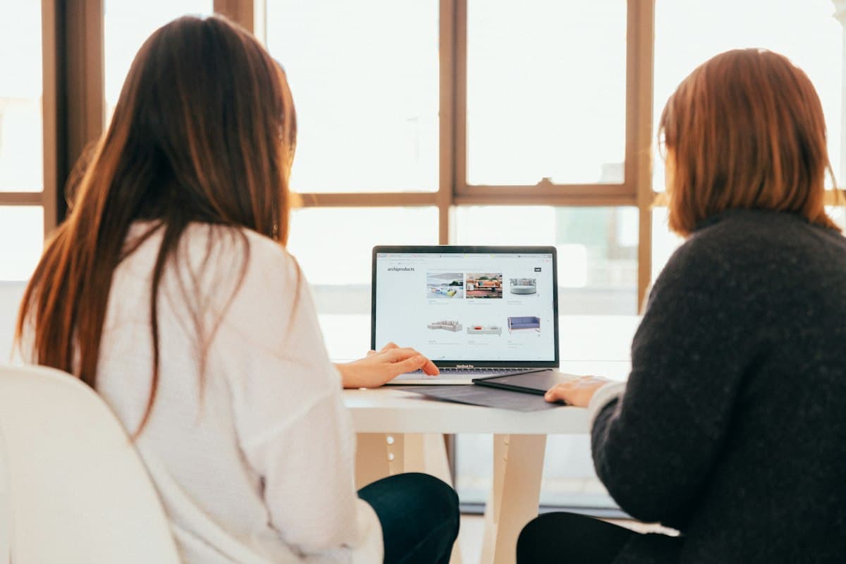 Two colleagues reviewing a schedule on a laptop